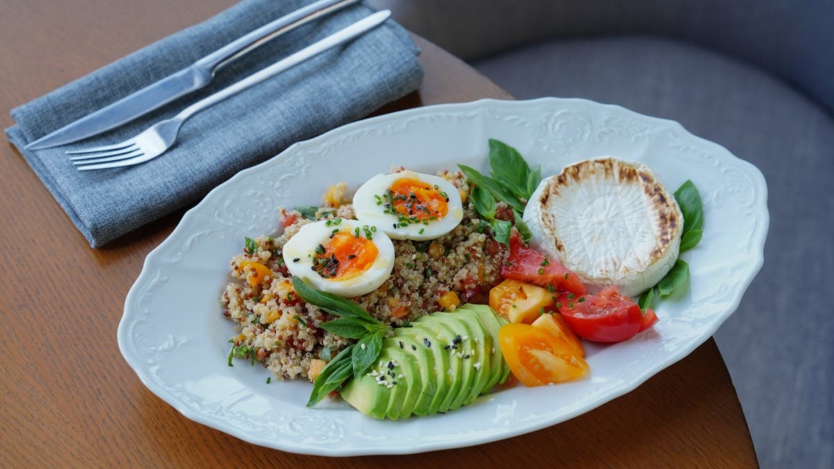 Delicious quinoa salad with sliced avocado, soft-boiled eggs, and fresh herbs.